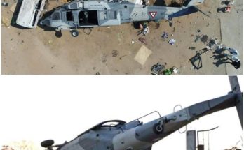 Overturned military helicopter crushing vehicles after crash in a residential area