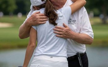 donald Trump in red MAGA cap hugs female golfer in white outfit on green course with
