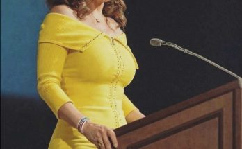woman in yellow dress speaks at podium during conference