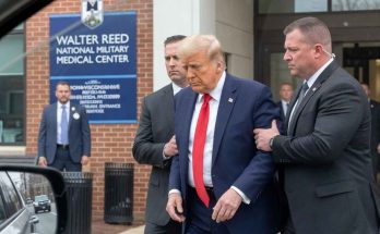 security escorts man in suit outside Walter Reed hospital